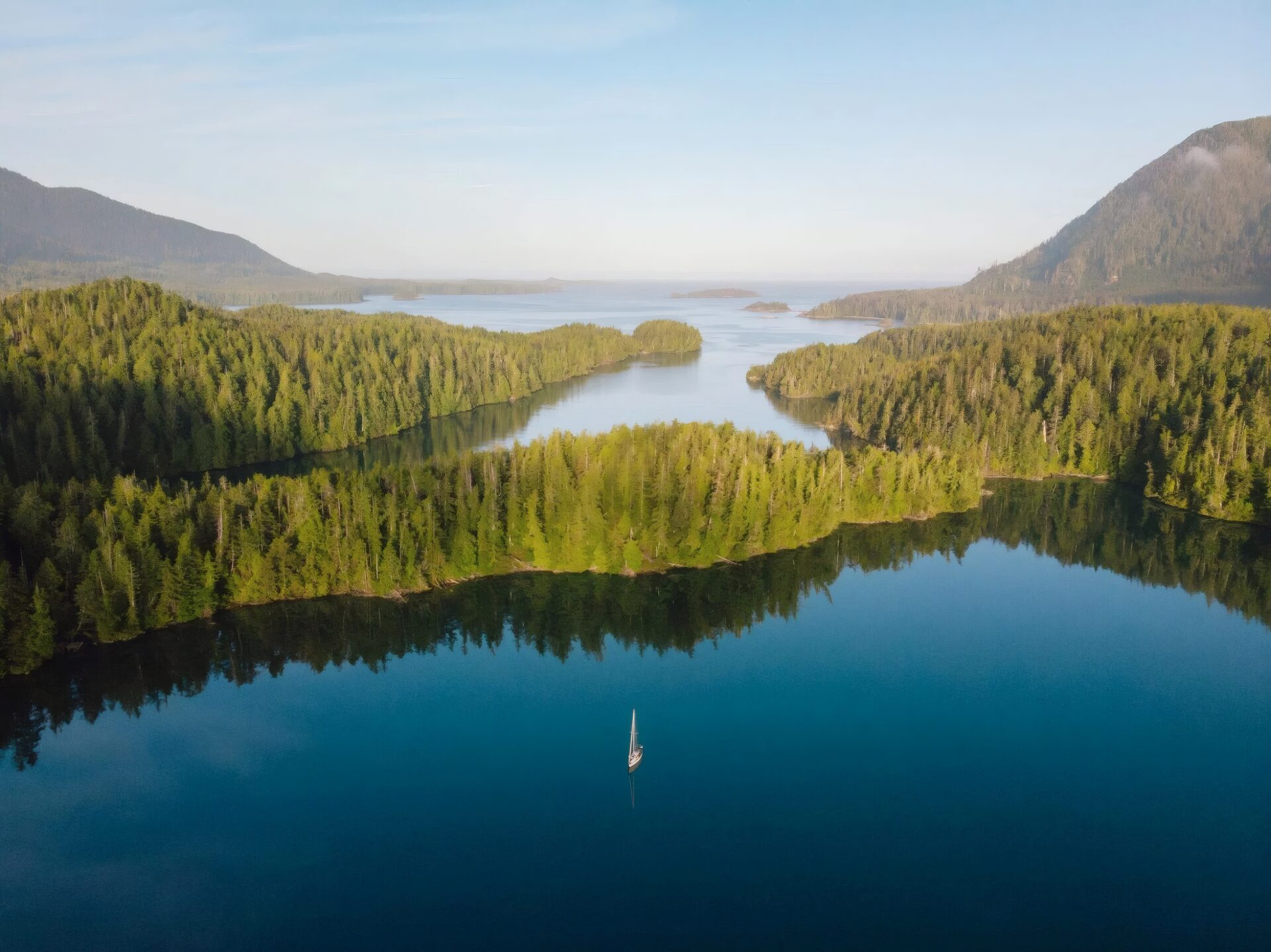 Winding channels and forested islands from the air, glassy at first light