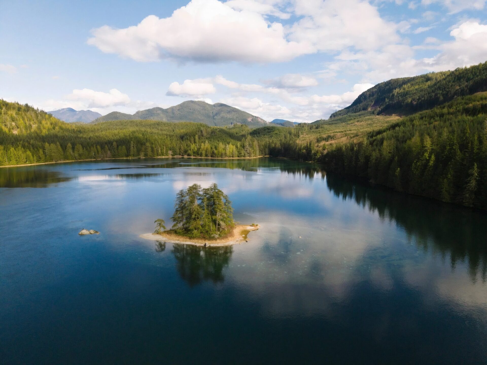 A small forested island resting on a mirror-calm lake